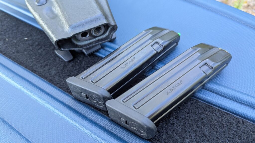 Close-up of two steel Mec-Gar Glock magazines resting on a blue Savior Equipment case next to the muzzle end of a Safariland holster.