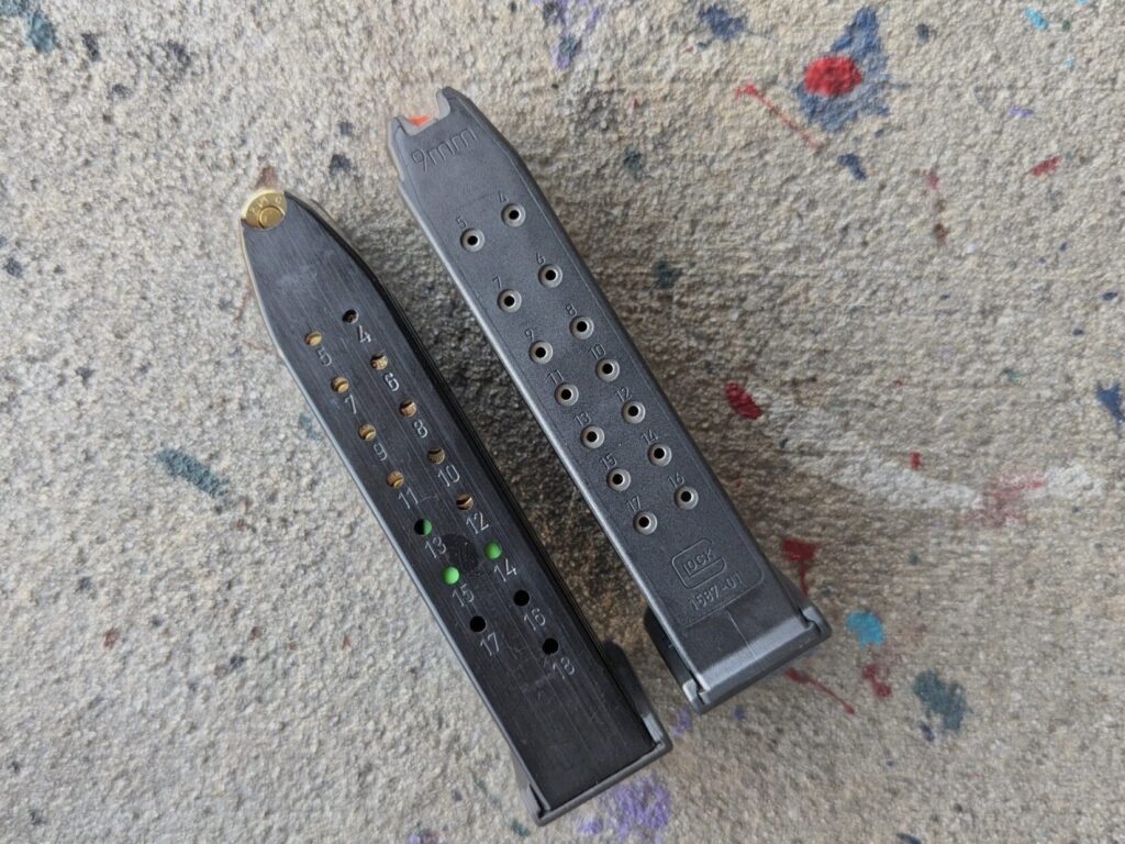 Comparison shot showing the back of a steel Mec-Gar magazine alongside a polymer Glock magazine to highlight the witness hole differences.