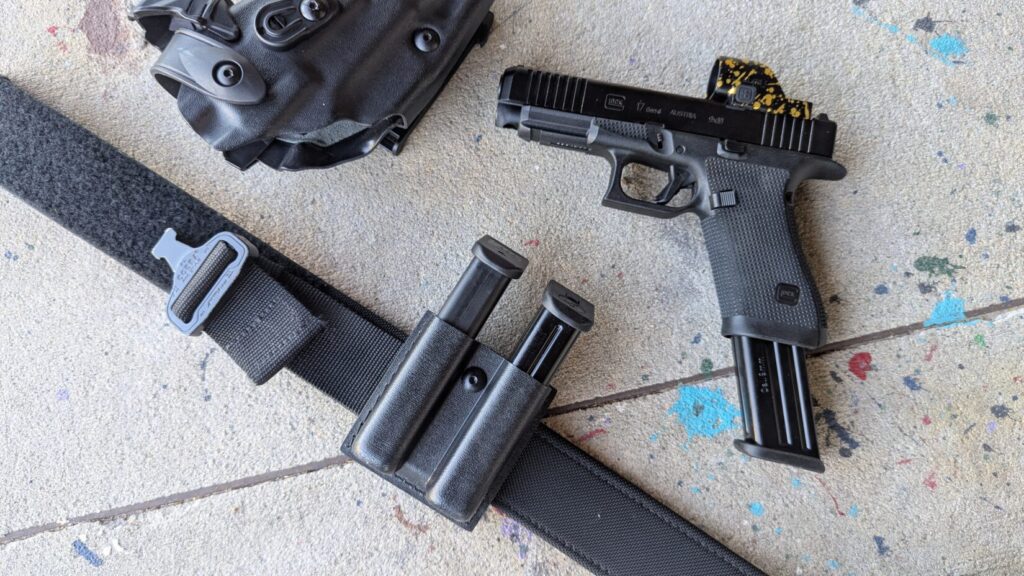 A Glock 17 displayed with three magazines: two steel Mec-Gar units and one standard polymer Glock magazine.