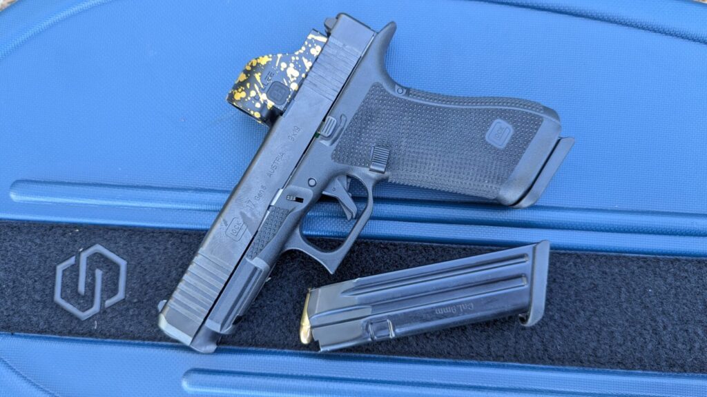 A Glock 17 with a custom optic resting on a blue Savior Equipment case next to a loaded Mec-Gar magazine.