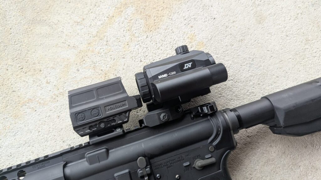 The NVMD-C200 mounted behind a Holosun 512C enclosed red dot sight on a black rifle.