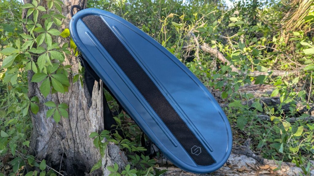 Side profile of the closed blue Savior Pro Touring case resting on a log in an outdoor setting.