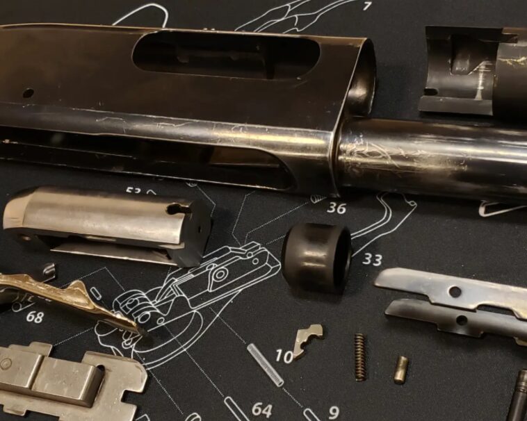 A shotgun disassembled on a mat