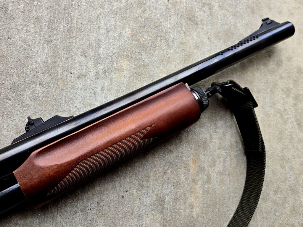 A barrel of a shotgun and forend against a concrete background
