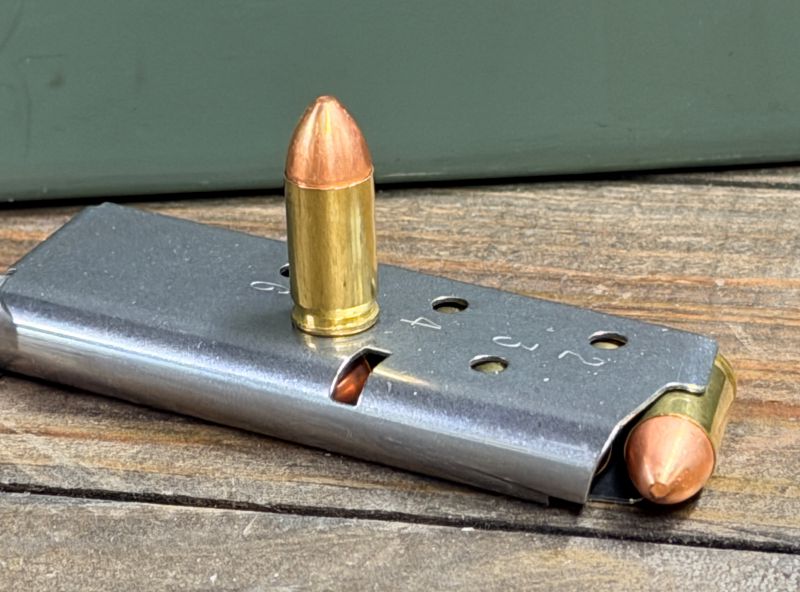A single bullet on top of a magazine to a .380 pistol. 