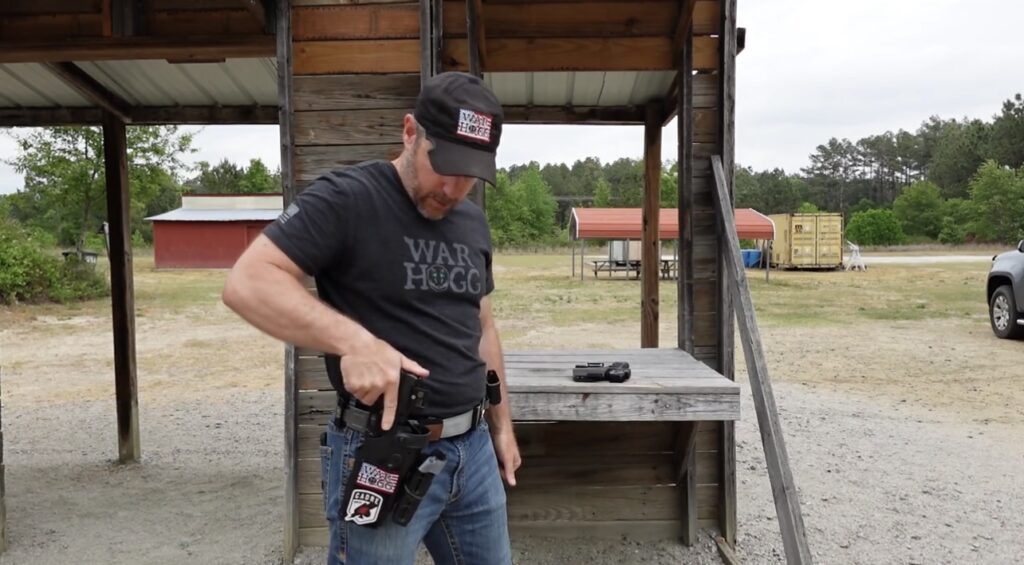 Pictured is Rick Hogg founder of War HOGG Tactical looking at his Safariland level III retention holster as he is reholstering his pistol.