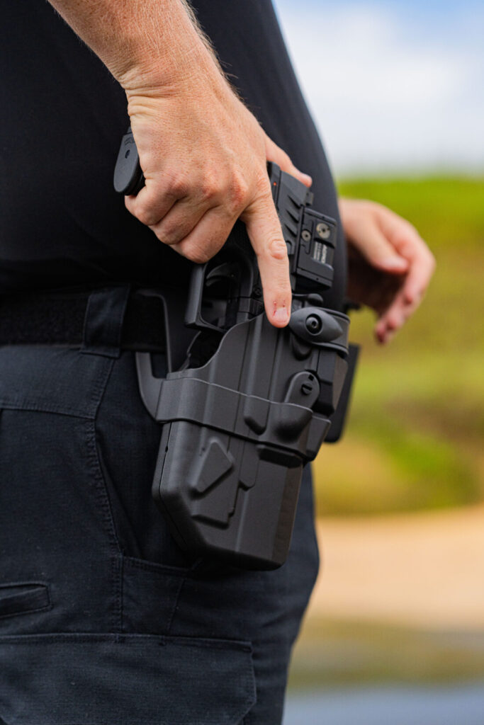Pictured is a War HOGG Tactical LEO student using good trigger finger discipline while reholstering his pistol.
