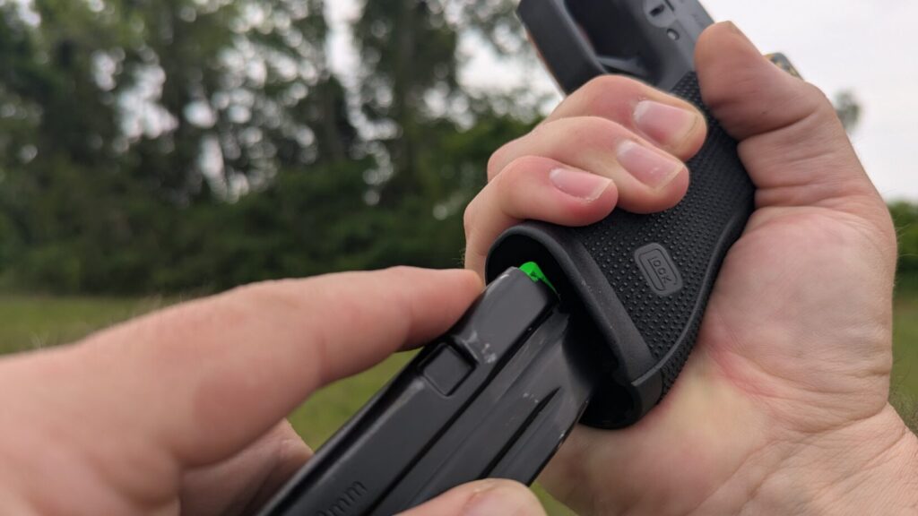 Detail shot of a hand gripping a black Glock pistol while the other hand guides a magazine into the magwell.