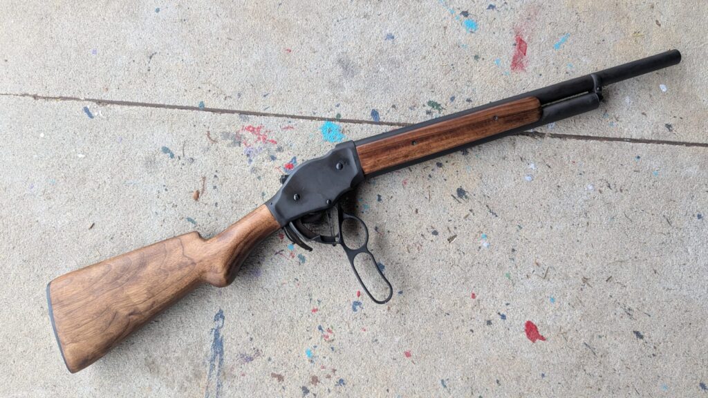 A lever-action shotgun with the action open, highlighting the wood grain and lever mechanism.
