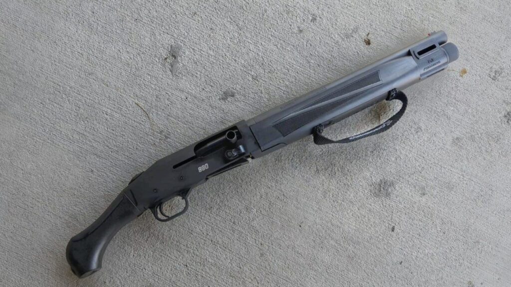 a 990 with a black finish and a raptor grip lying on a plain concrete surface.
