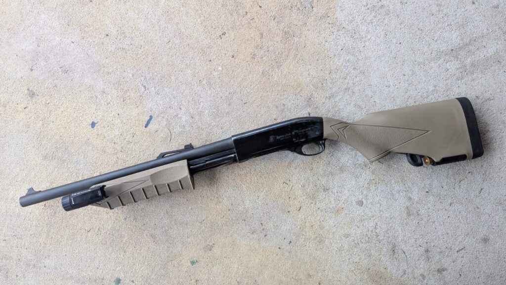 A full profile of a Remington 870 shotgun featuring a tan tactical stock and forend with a mounted weapon light.