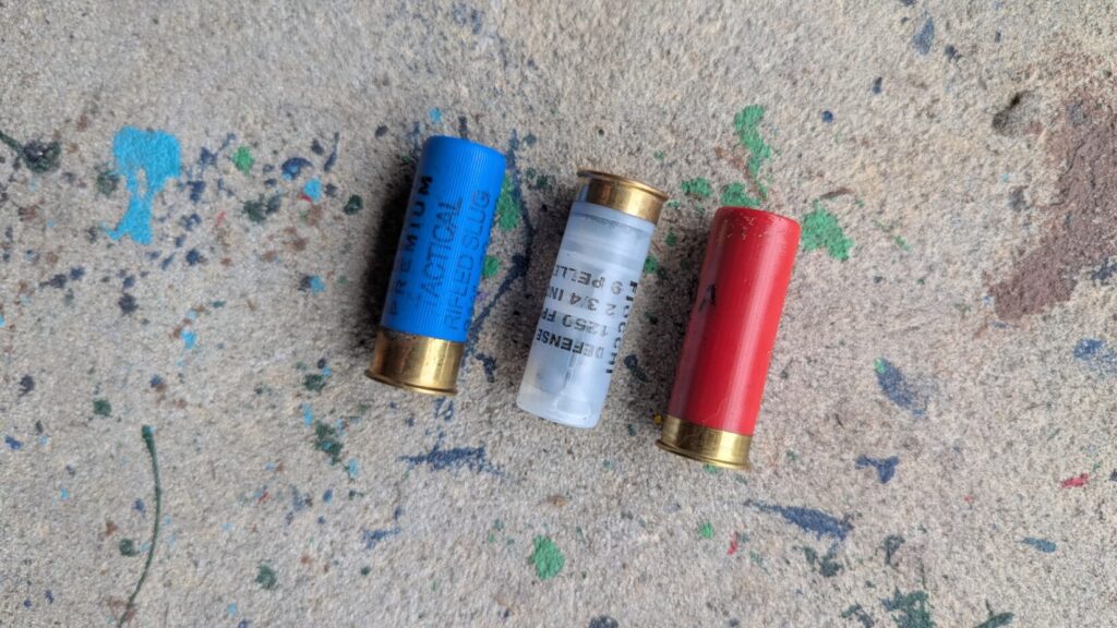 three shotgun shells lying on paint speckled concrete