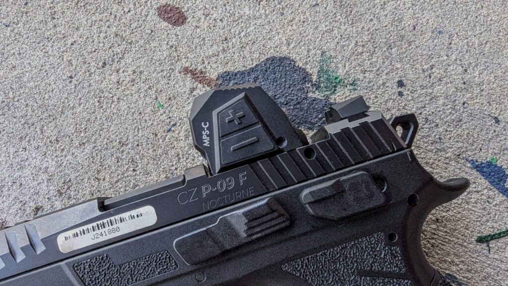 A side-on shot of the CZ P-09 F being held in a two-handed grip, showing the enclosed emitter design of the Steiner MPS-C optic.