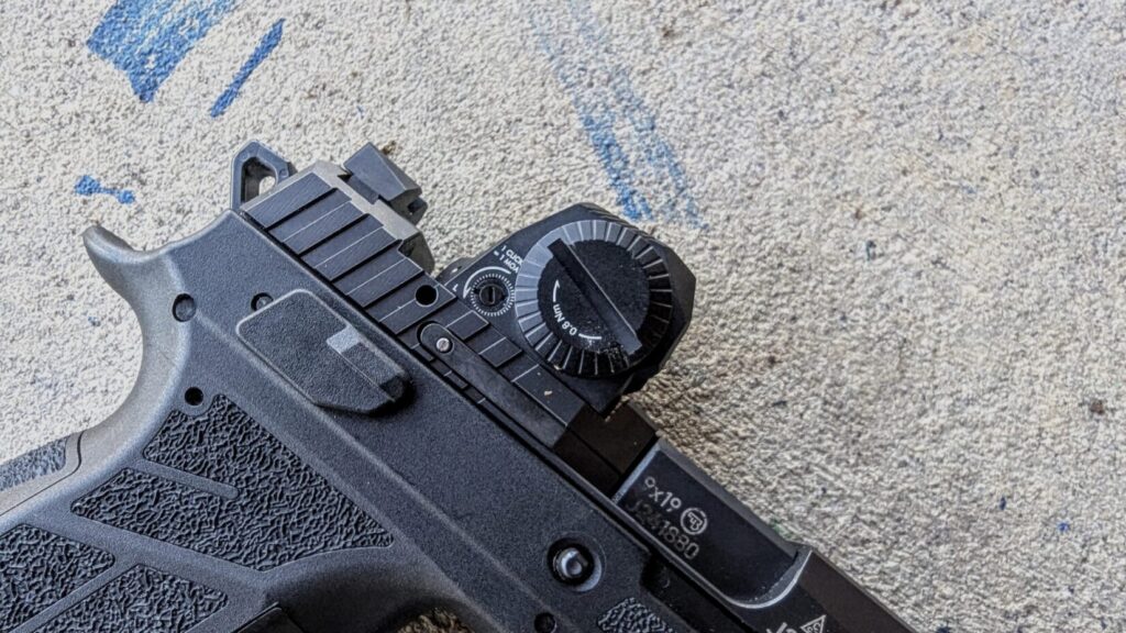 A clean side profile of the optic mounted on the Nocturne slide, resting on a textured concrete surface.
