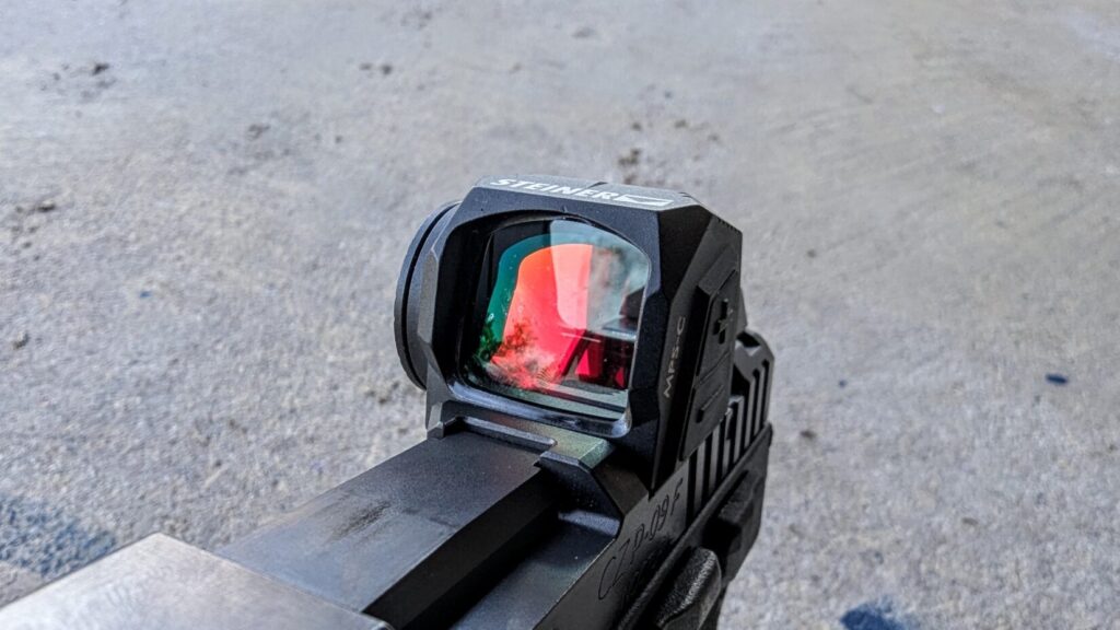 A front-quarter view of the optic, showing the objective lens with a reddish-orange multi-coating reflection.
