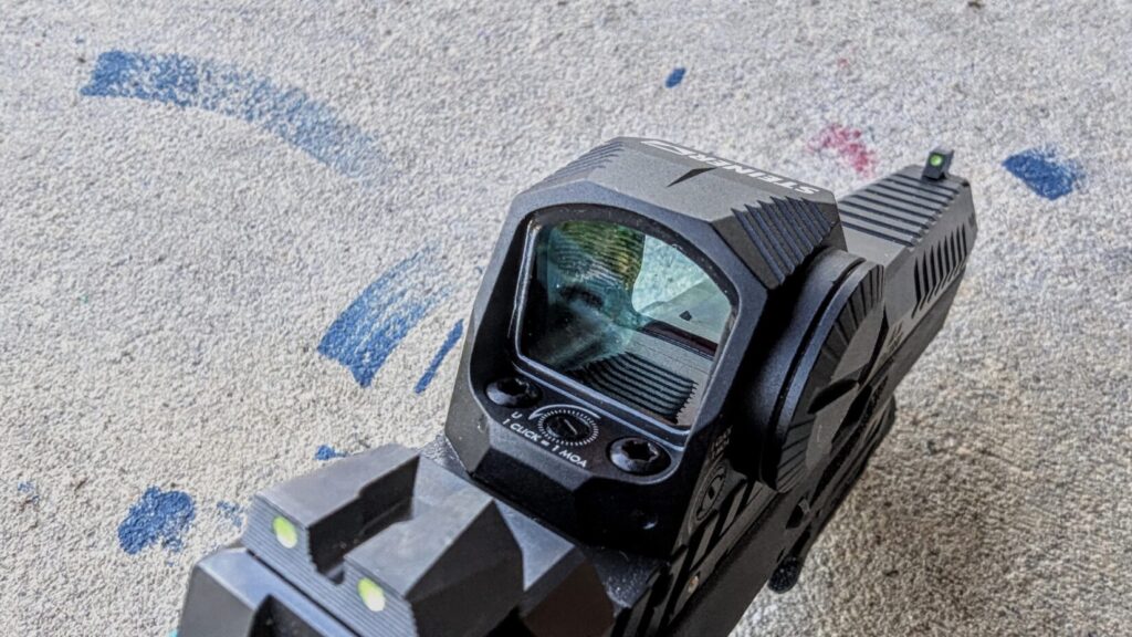 A high-angle close-up from the rear, showing the windage/elevation adjustment dials and the top of the enclosed optic housing.
