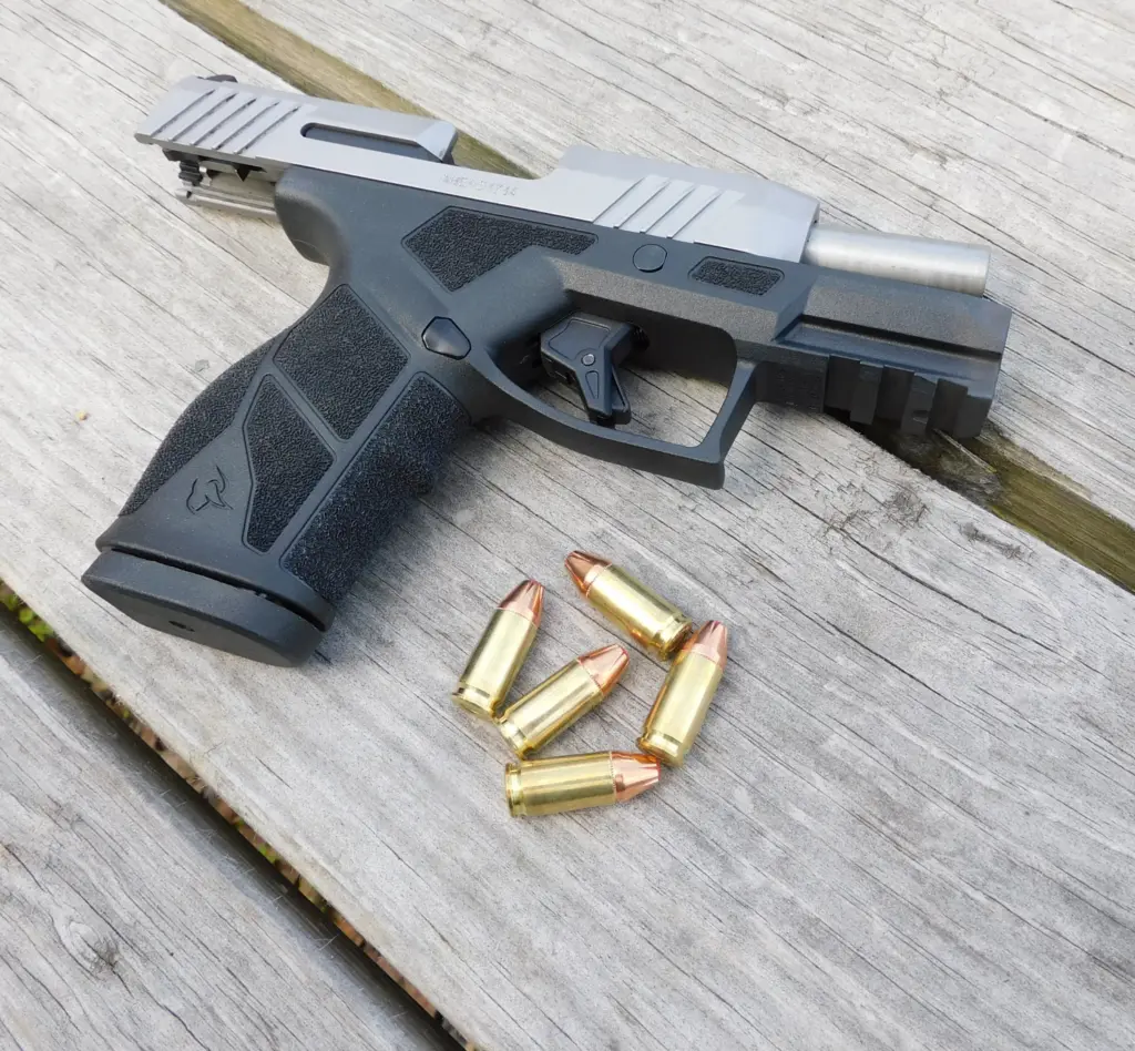 A Taurus GX2 pistol with the slide locked back next to some ammunition cartridges