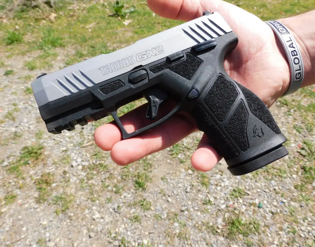 A Taurus GX2 pistol resting on a man's hand