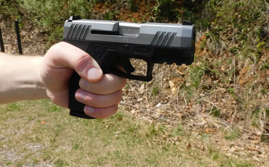 A man's hand holding a semiautomatic pistol