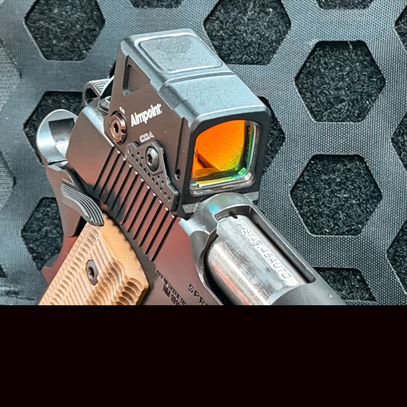 A close up view of the Aimpoint COA red dot mounted on the Operator 1911 with a black background. 
