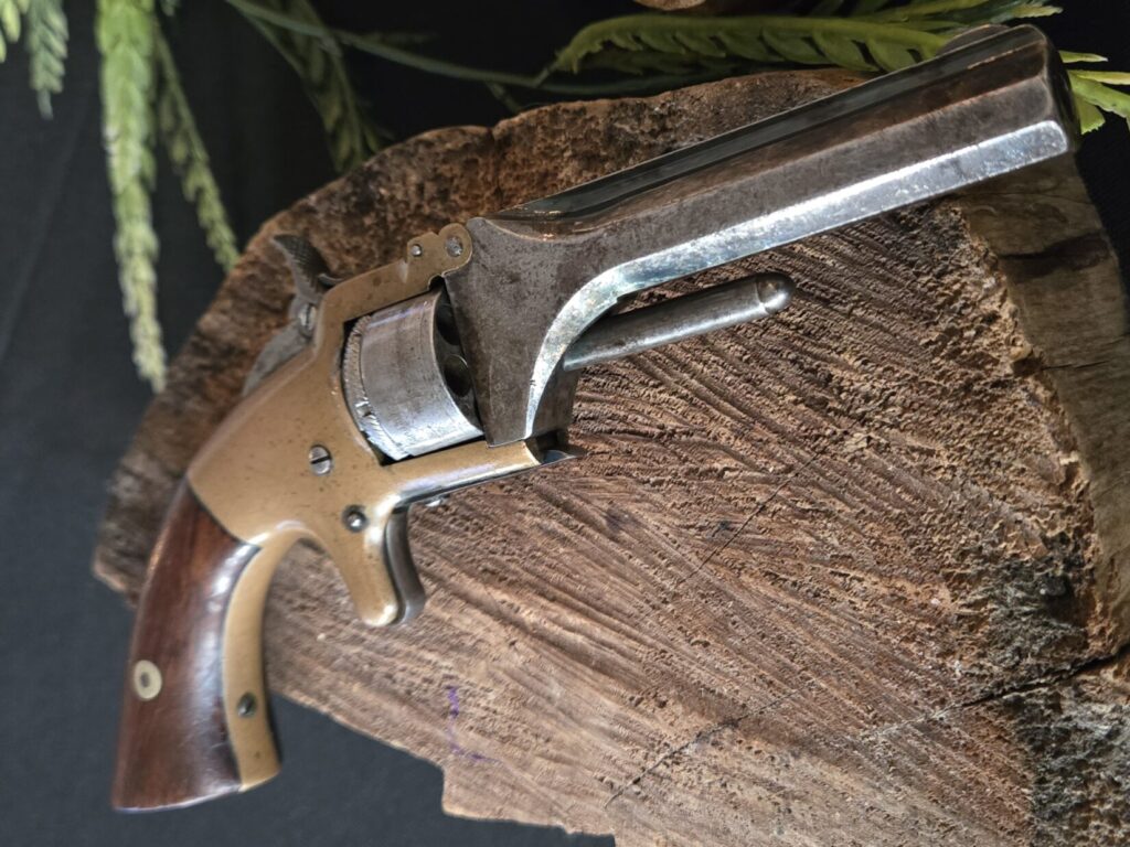 A Smith & Wesson Model 1 on top of a wooden backdrop