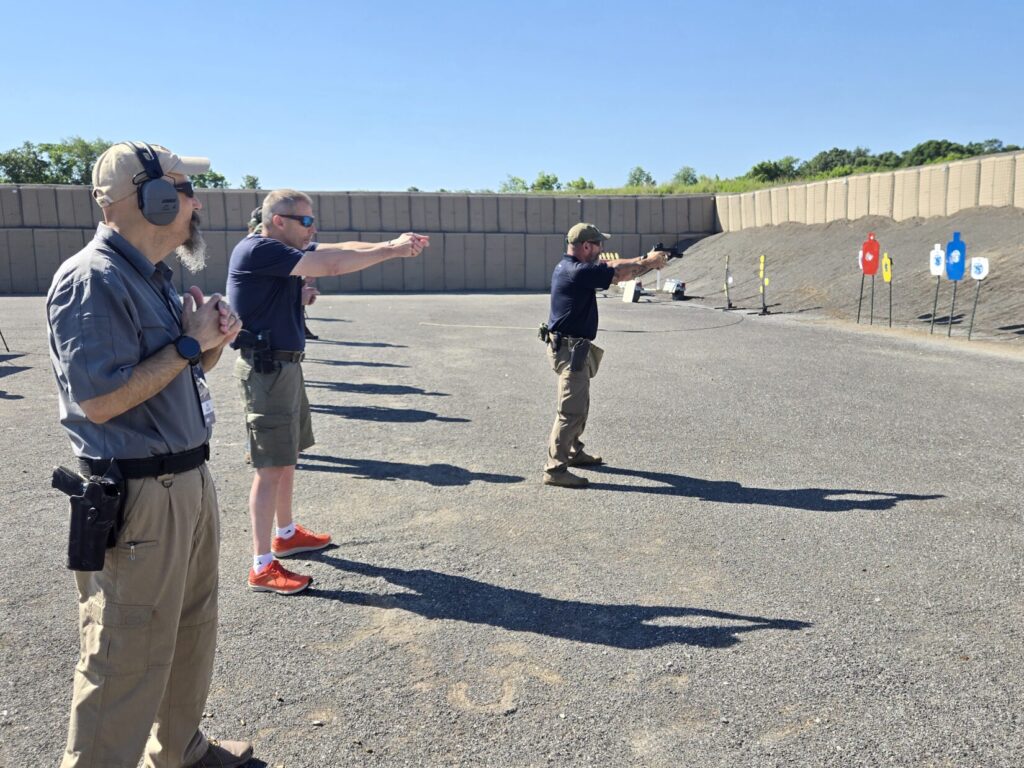 A shooting instructor demonstrating a course of fire in front of a class on a range
