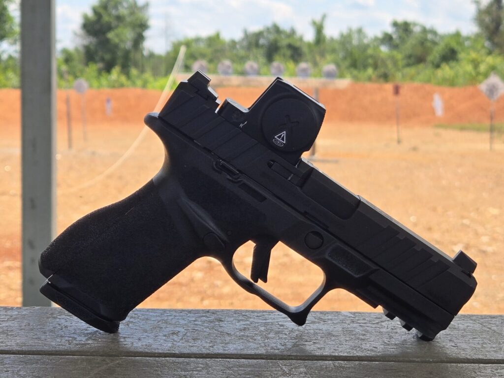 A dark silhouette of a pistol with red dot at a plate rack