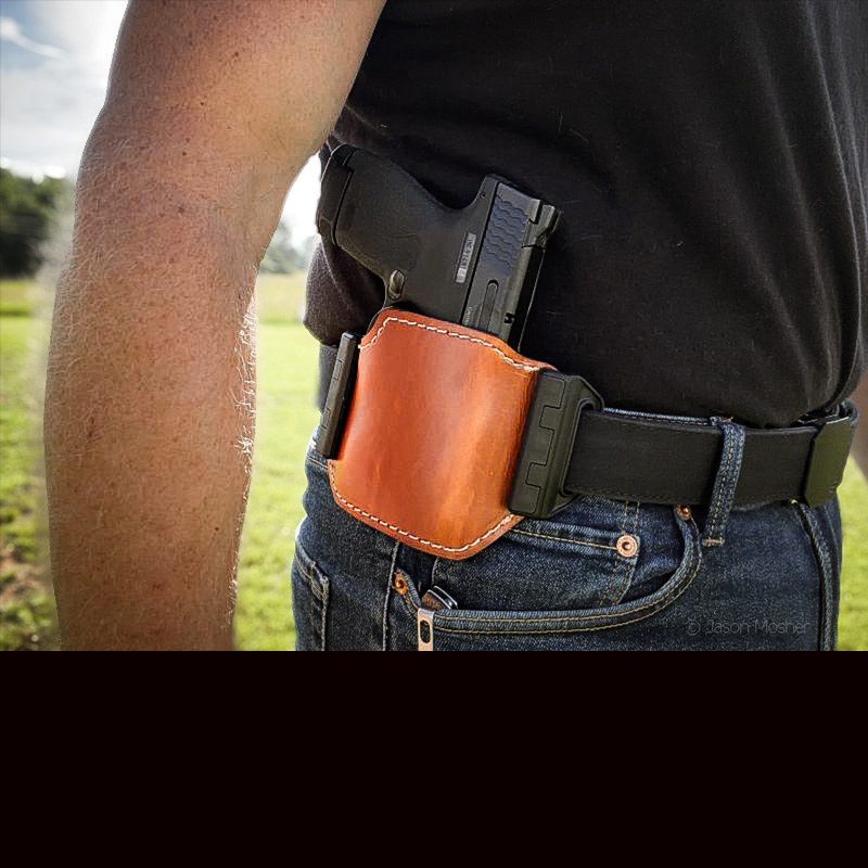 A person in jeans and a black shirt, wearing the Shenandoah holster on their side.