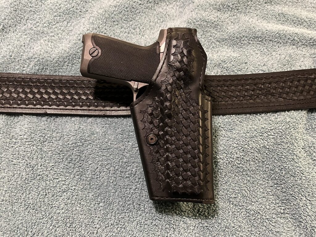 Image of a black Safariland M-200 thumb break duty holster on a Safariland duty belt, both in basketweave pattern. There is a Ruger P94DAO pistol in the holster.