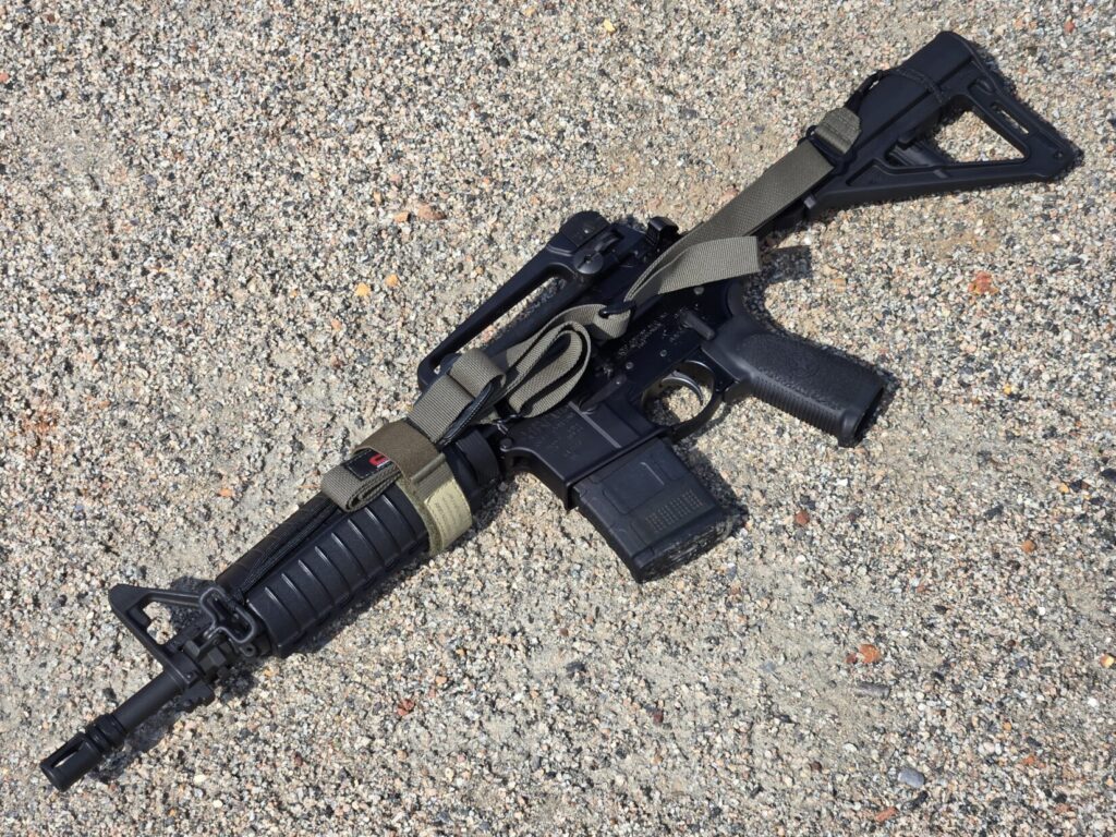 An AR15 firearm with a ranger green sling attached to the side.