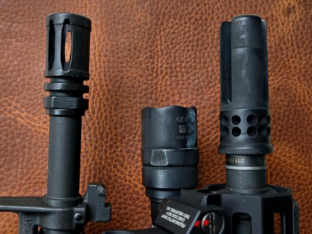 Two AR15 muzzles with a flashlight and front of a back up iron sight.