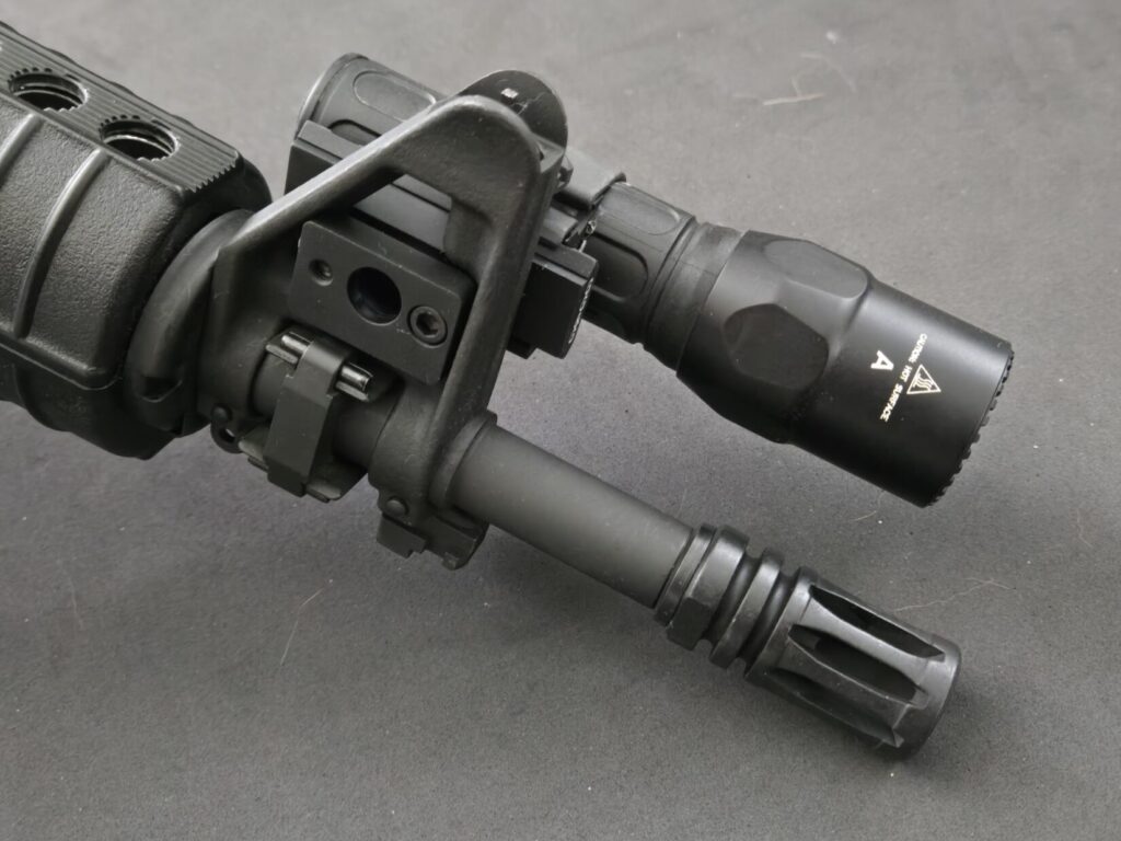 A rifle front sight with surefire light and a2 bird cage flashider.