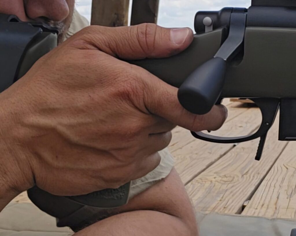 A hand placed on a rifle with the thumb on the same side as the bolt.