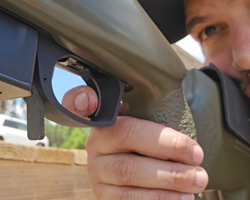 A man behind a rifle with his finger on the trigger