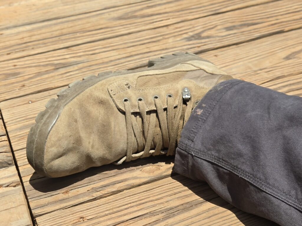 A desert boot flat against a wooden platform.