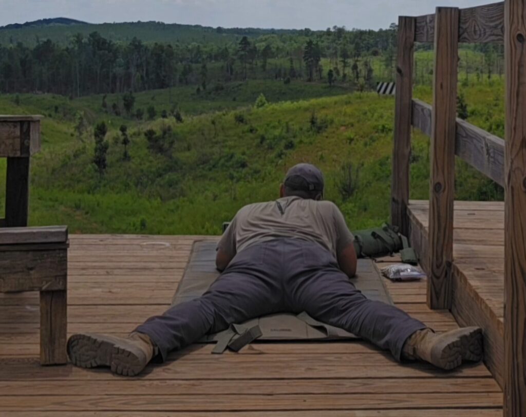 A shooter on a platform in the prone position with targets in the background