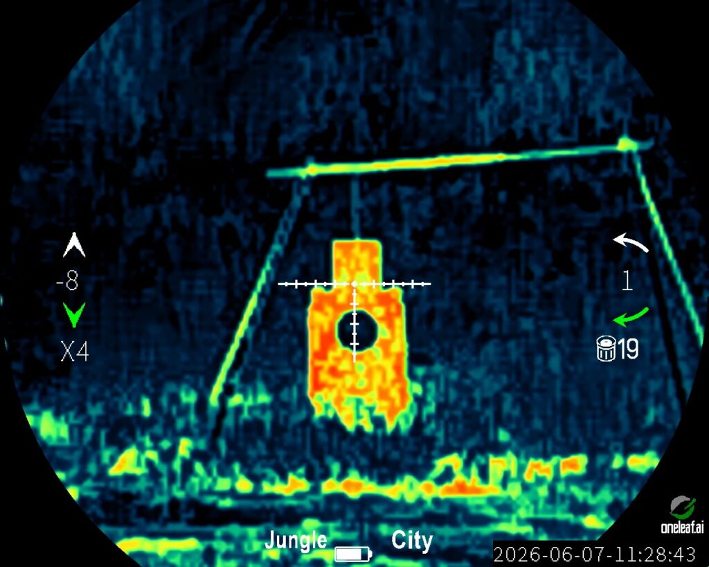 Thermal optic view at 4x digital zoom ($X4$) in "Jungle" mode and "City" environment. The crosshairs are centered on a close-up, bright orange and yellow torso-shaped shooting target.