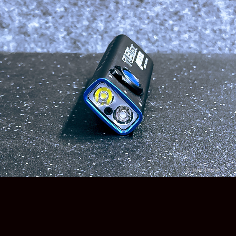 A view of the bezel of a black flashlight with blue outlines on a black table.