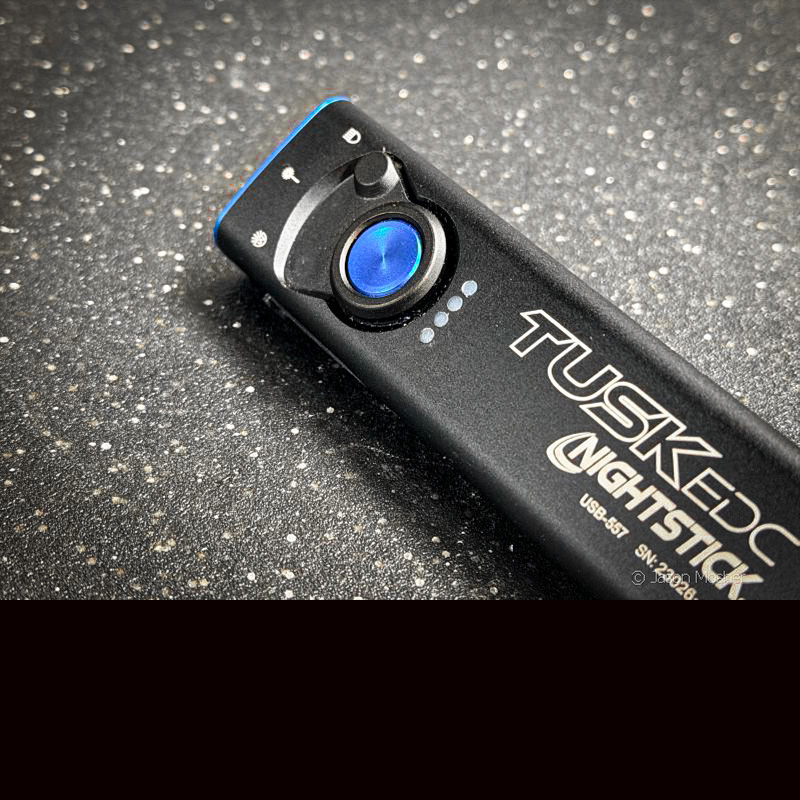 The top of a black light with a blue power button on a black table.