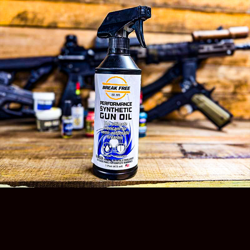 A brown bottle with a white label that reads "Break Free Gun Oil" on a wooden table.