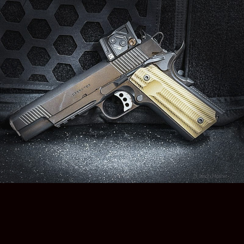 A black handgun with green grips leaning up against a black backpack. 