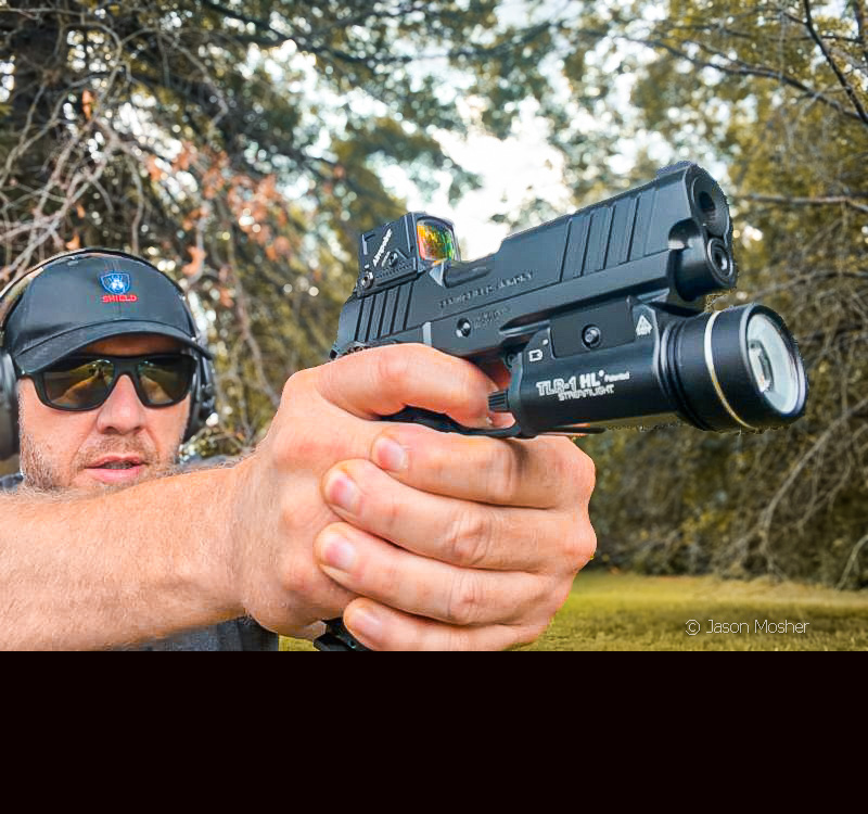 A person in a black hat and sunglasses shooting the Prodigy 1911 pistol.