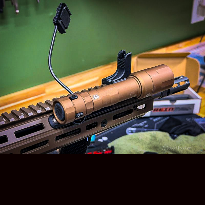 The REIN light mounted to a rifle with the wire for the remote button sticking up in the air. 