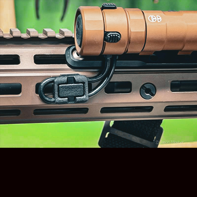 The REIN light mounted to a rifle, with a close up of the wires underneath, attached to the rail using a black wire management clamp. 