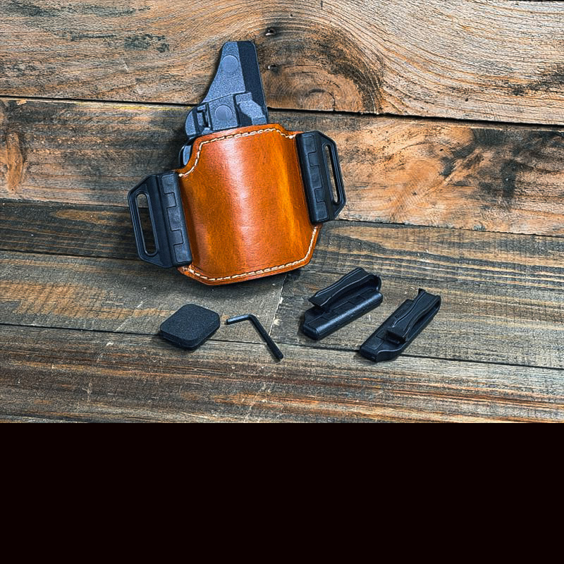 A brown leather holster with black plastic slips on each side of it, leaning up against a wood wall.