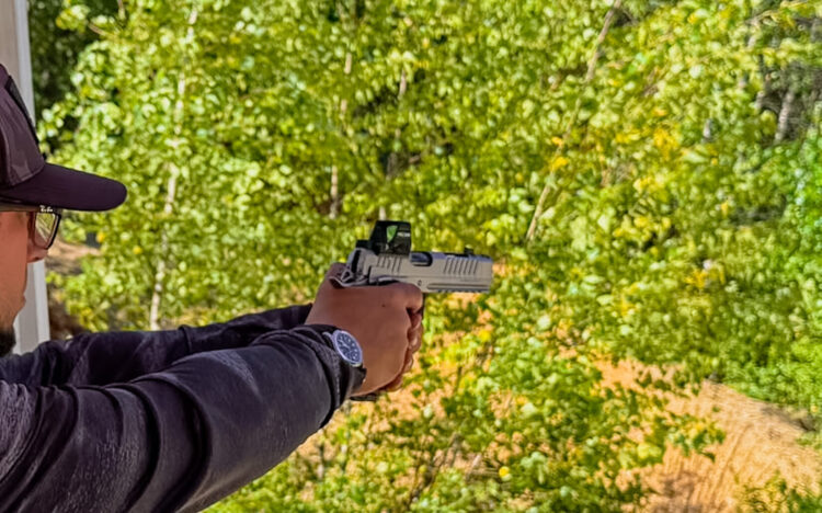 Man shooting a pistol outside.