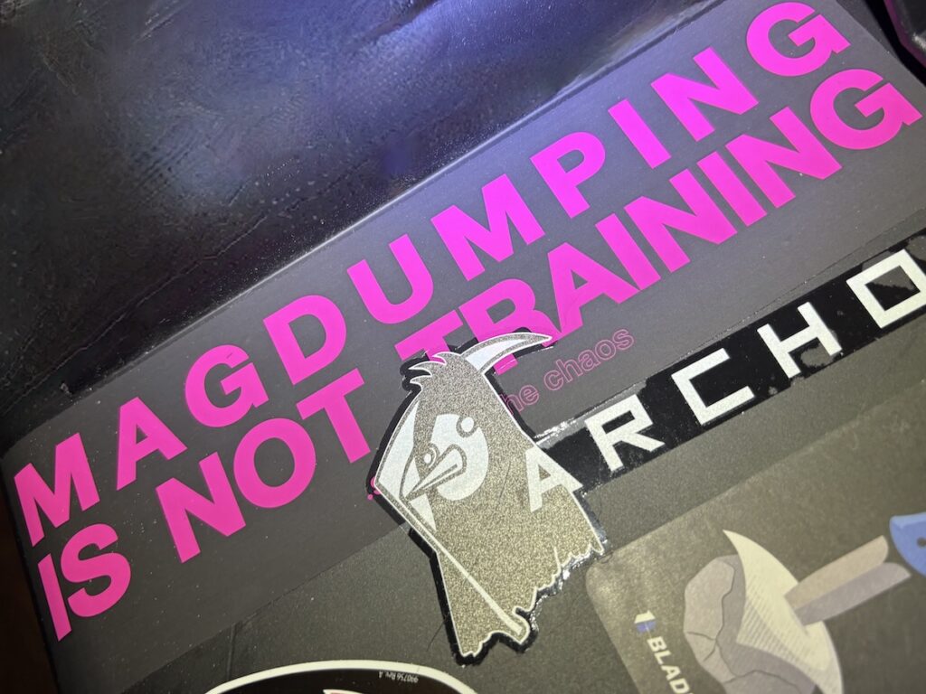A bumper sticker reading 'Mag Dumping is not Training,' making the point that recoil control drills alone don't prepare you for a real encounter