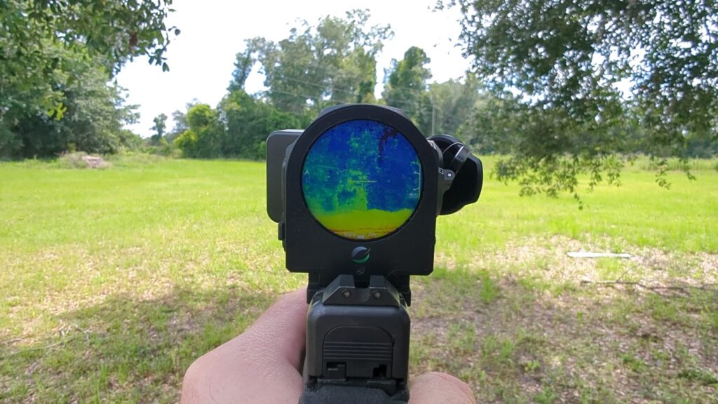 First-person perspective looking directly through the circular display of the Mars Mini thermal optic mounted on a Glock pistol, showing a multicolored