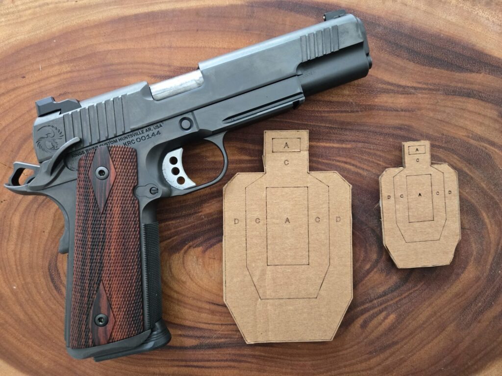 A pistol and a couple smaller targets for dry fire on a wood backdrop