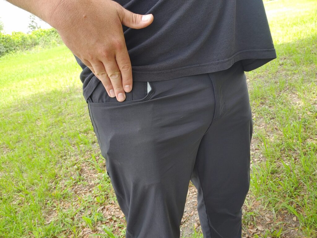 Close-up side view of a man resting his right hand naturally against his thigh just above the front pocket line, with a slight protrusion from a concealed firearm visible.